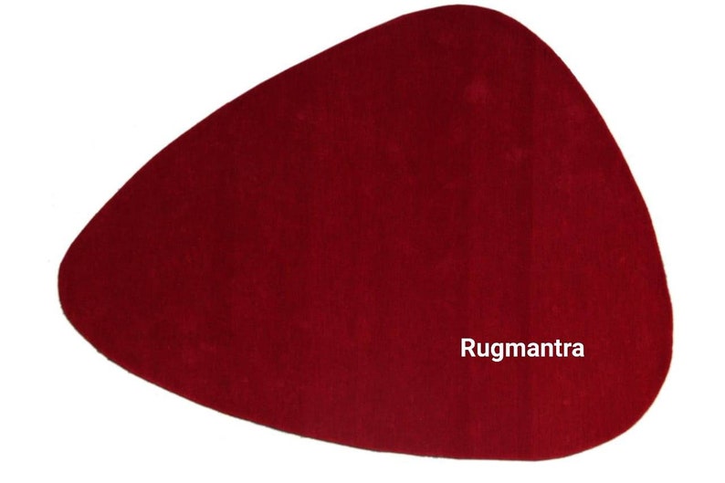 May include: A solid red, free-form shaped rug with the text "Rugmantra" in white lettering.