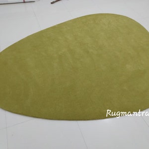 May include: A large, green, oval-shaped rug with a soft, plush texture. The rug is made of a high-quality material and is perfect for adding a touch of color and comfort to any room.