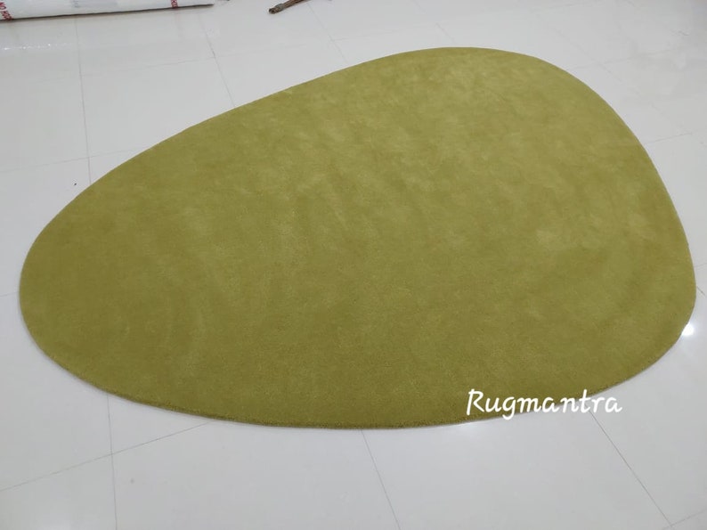 May include: A large, green, oval-shaped rug with a soft, plush texture. The rug is made of a high-quality material and is perfect for adding a touch of color and comfort to any room.