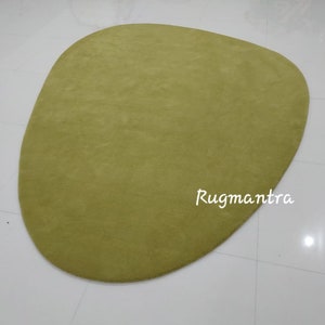 May include: A large, green, oval-shaped rug with a soft, plush texture. The rug is made of a high-quality material and is perfect for adding a touch of color and comfort to any room.