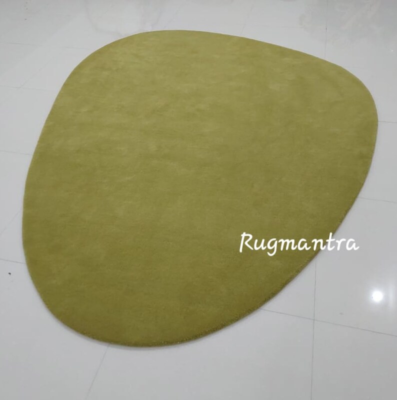 May include: A large, green, oval-shaped rug with a soft, plush texture. The rug is made of a high-quality material and is perfect for adding a touch of color and comfort to any room.