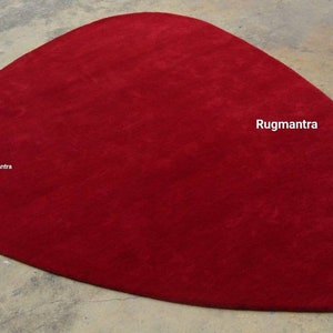 May include: A large, red, oval-shaped rug. The rug is made of a soft, plush material. The rug is perfect for adding a touch of color and style to any room.