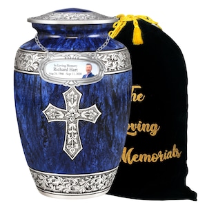 Könnte beinhalten: Blaue Urne mit einem silbernen Kreuzdesign und einer silbernen Plakette mit einem Foto und der Inschrift "In Loving Memory Richard Hart Aug 24, 1946 - Sept 11, 2020". Die Urne wird mit einem schwarzen Samtbeutel mit goldenen Lettern geliefert, auf dem "The Loving Memorials" steht.