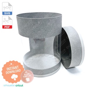 以下が含まれることがあります： 透明なプラスチック製の窓が付いた灰色の厚紙の円筒形。円筒形は開いており、上部は横に置かれています。円筒形はクラフトプロジェクト用の空白のテンプレートです。