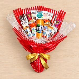 Könnte beinhalten: Ein Blumenstrauß-Arrangement mit einer zentralen orangefarbenen Fanta-Dose, umgeben von verschiedenen Kinder-Schokoriegeln, Kinder Country-Riegeln und Kinder-Überraschungseiern. Alles ist in rot-weiß gestreiftes Papier mit weißem Netz eingewickelt.