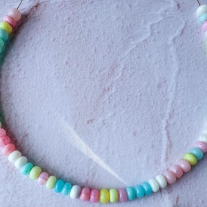 Puede incluir: Un collar de cuentas de colores pastel con colores alternos de azul claro, rosa, amarillo y blanco.