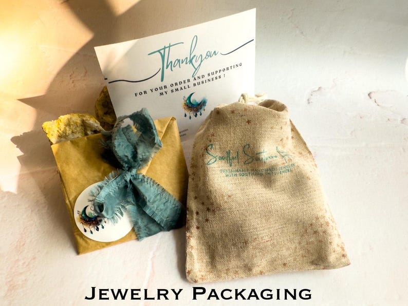 May include: A brown paper bag with a blue ribbon and a sticker with a moon and stars design. The bag is sitting on a white surface next to a burlap bag with a logo that says "Soulful Siren" and a thank you card that says "Thank you for your order and supporting my small business!"