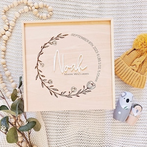 May include: A wooden keepsake box with a floral design and the name "Noah" engraved on it. The box also includes the date "September 8th, 2023", time "5:05 AM", and weight "6 LBS 2 OZ".
