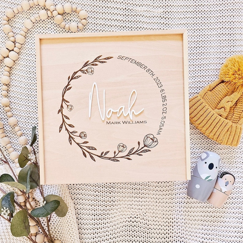 May include: A wooden keepsake box with a floral design and the name "Noah" engraved on it. The box also includes the date "September 8th, 2023", time "5:05 AM", and weight "6 LBS 2 OZ".