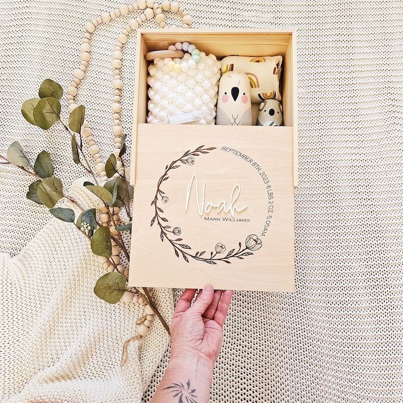 May include: A wooden keepsake box with a floral design and the name "Noah" engraved on it. The box also includes the date "September 8th, 2023", weight "6 lbs 2 oz", and time "5:05 AM".