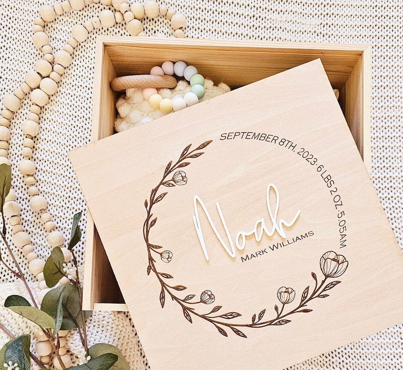 May include: A wooden keepsake box with a floral design engraved on the lid. The lid reads "Noah, Mark Williams, September 8th, 2023, 6 lbs 2 oz, 5:05 AM".