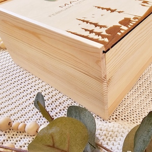 May include: A wooden box with a lid, the lid is decorated with a laser-engraved design of trees, birds, and bears. The text "MAY FEBRUARY 10TH" is engraved on the lid.