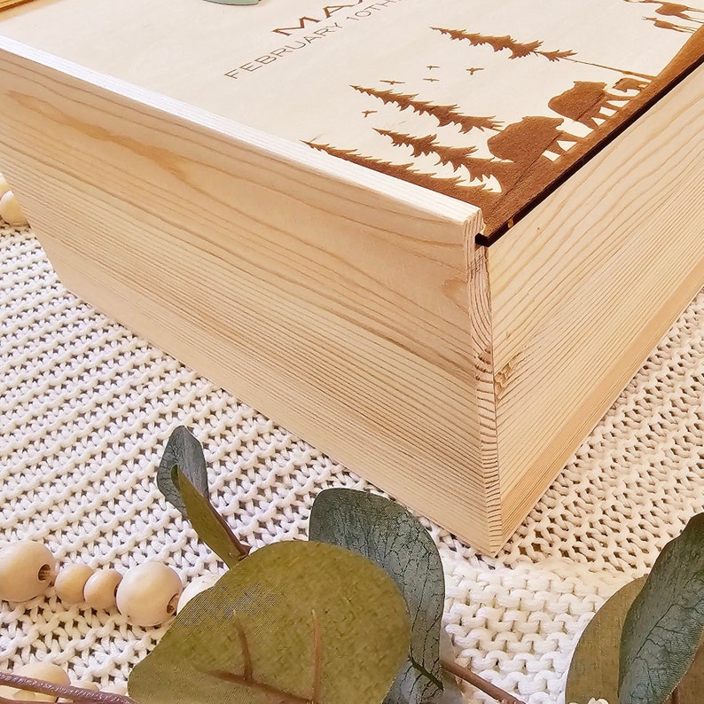 May include: A wooden box with a lid, the lid is decorated with a laser-engraved design of trees, birds, and bears. The text "MAY FEBRUARY 10TH" is engraved on the lid.