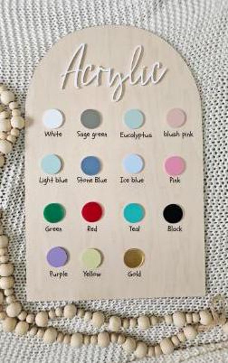 May include: A wooden sign with the word "Acrylic" at the top. The sign has 12 colour swatches, each with a name below it. The colours are: white, sage green, eucalyptus, blush pink, light blue, stone blue, ice blue, pink, green, red, teal, black, purple, yellow, and gold.