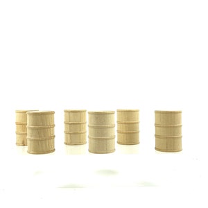 May include: A collection of six small, unfinished wooden barrels. Each barrel has a cylindrical shape with horizontal bands, and is made of light-colored wood. The barrels are arranged on a white surface.