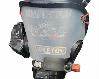 Op de afbeelding: Een zwart en helder gezichtsmasker met de tekst "Templeton Rescue" en een logo van de brandweer van Denver. Het masker heeft rode bandjes en een rode knop. Het woord "SCOTT" is zichtbaar aan de bovenkant van het masker.
