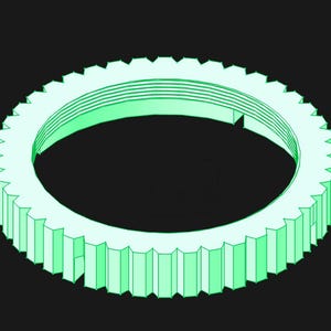 May include: A pale mint green circular gear component featuring a series of uniform vertical teeth along its outer edge and a set of concentric circular grooves visible on the inner surface of the ring, presented against a solid black background.