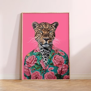 May include: A digital art print featuring a leopard wearing a floral patterned shirt against a pink background. The print is framed in a light wood frame.