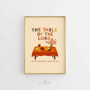 Peut inclure: Impression d'art encadrée avec le texte "THE TABLE OF THE LORD" en orange et vert. L'image représente une table dressée avec des verres à vin, du pain et des raisins. Le texte "HE HAS PREPARED A TABLE FOR YOU" est en bas.