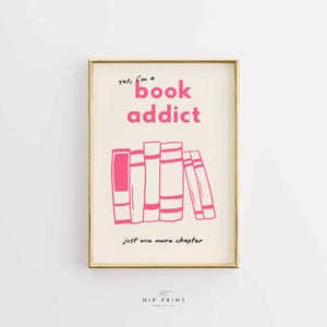 May include: A framed print with a gold border. The print features the text "yes, I'm a book addict" in pink, above a pink illustration of a stack of books. Below the books is the text "just one more chapter".