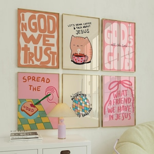 May include: Six framed art prints with gold frames, displaying colourful text and illustrations. The prints feature phrases such as "In God We Trust" and "Let's Drink Coffee & Talk About Jesus." The colour palette includes pink, orange, and beige.