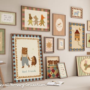 May include: A collection of framed art prints with whimsical illustrations, including animals, houses, and inspirational quotes. The color palette features soft pastels and earth tones, creating a cozy nursery theme. The text "Best Friends" is visible on one print.