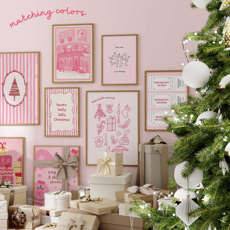 May include: A collection of framed pink and white Christmas-themed art prints and gift boxes. The prints feature festive illustrations and text, including "Have a Holly Jolly Christmas" and "the best mood". A decorated Christmas tree with white ornaments is in the background.