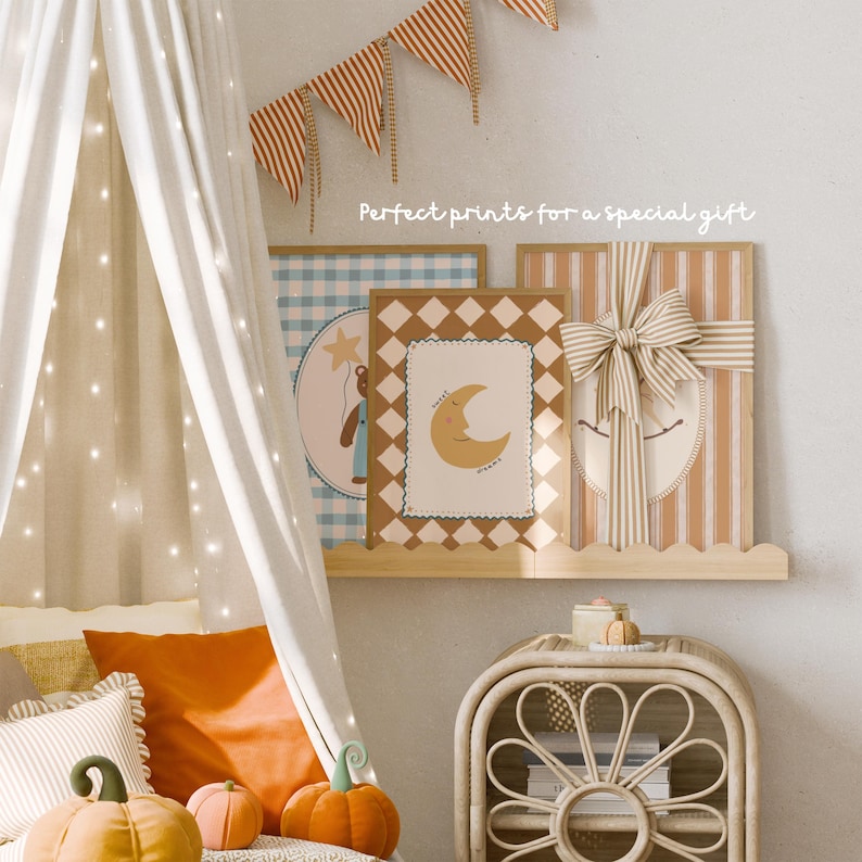 May include: Three framed prints on a wooden shelf, with the text "Perfect prints for a special gift." The prints feature a bear with a star, a crescent moon, and a striped design with a bow. Decorative pumpkins and pillows are in the foreground.