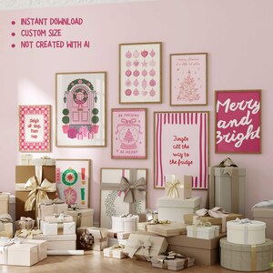 May include: A collection of framed Christmas-themed art prints in shades of pink and white, with festive illustrations and text. The prints are displayed on a pink wall, surrounded by wrapped gift boxes with ribbons.