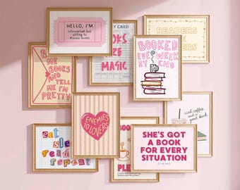May include: A collection of framed art prints with gold frames, featuring various book-themed quotes and illustrations in pink, white, and yellow. The prints include phrases like "Hello, I'm introverted but willing to discuss books" and "Enemies to Lovers."