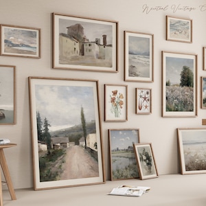 May include: A gallery wall featuring a collection of vintage-style framed prints. The prints depict various landscapes, seascapes, and botanical illustrations. The frames are all in a light wood tone and are arranged in a symmetrical pattern on a white wall.