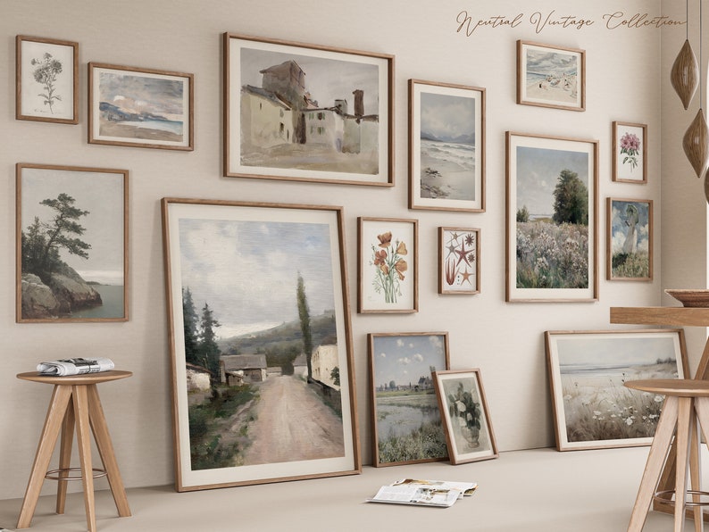 May include: A gallery wall featuring a collection of vintage-style framed prints. The prints depict various landscapes, seascapes, and botanical illustrations. The frames are all in a light wood tone and are arranged in a symmetrical pattern on a white wall.