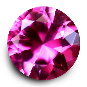 May include: A round, faceted gemstone in a vibrant, deep pink colour. The gem's intricate cuts reflect light, creating a dazzling display of colour and sparkle. The gemstone is set against a white background.
