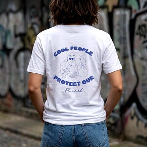 Könnte beinhalten: Ein weißes Kurzarm-T-Shirt mit einer blauen Grafik auf der Rückseite. Das Design zeigt eine Comic-Weltkugel, die eine Plastikflasche und einen Müllbeutel hält, mit dem in blauer Schrift gedruckten Text COOL PEOPLE PROTECT OUR Planet.