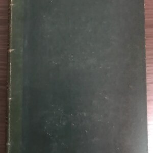 May include: A vintage hardcover book with a dark green cover. The book's spine is a lighter shade of green, and the cover shows signs of wear and age. The book is closed and appears to be in good condition.