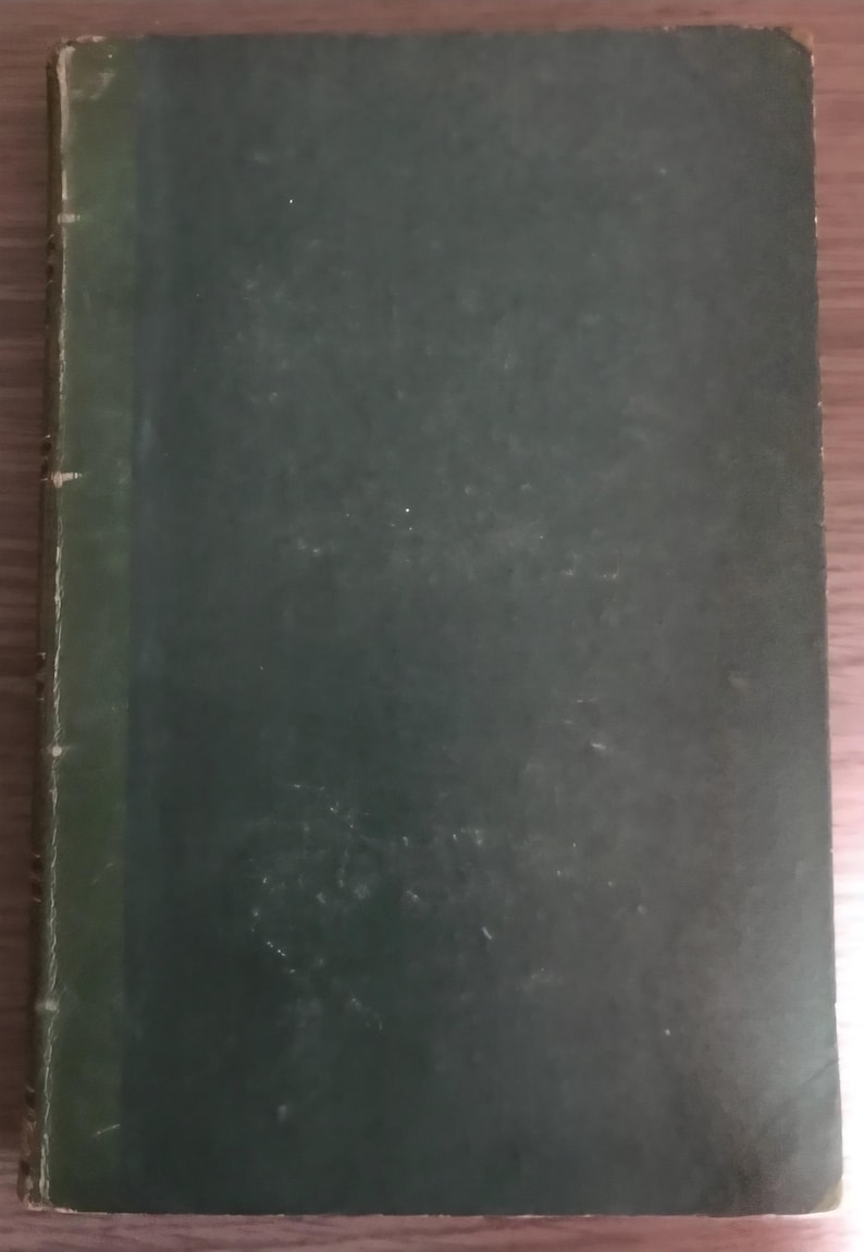 May include: A vintage hardcover book with a dark green cover. The book's spine is a lighter shade of green, and the cover shows signs of wear and age. The book is closed and appears to be in good condition.