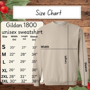 May include: A tan Gildan 1800 unisex sweatshirt with a size chart. The size chart shows measurements in inches for width, length, and sleeve for sizes S through 3XL. The sweatshirt is displayed on a wooden background.