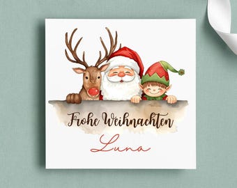 May include: A square Christmas card featuring Santa Claus, a reindeer, and an elf. The characters are peeking over a banner that reads "Frohe Weihnachten Luna" in a watercolor style. The card has a white background.