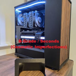 Może przedstawiać: Czarna obudowa komputera z drewnianym panelem bocznym, podświetlona niebieskim oświetleniem wewnętrznym. Obudowa mieści wiele wentylatorów i komponentów, z widocznym tekstem "B-Grade / Seconds (Cosmetic Imperfections)". Czarny element z przodu.