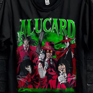 Può includere: T-shirt nera con una grafica di personaggi anime in rosso e verde, con la scritta "ALUCARD" in verde. La t-shirt è appesa a una gruccia nera. L'immagine include testo promozionale per sconti.