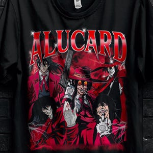 Può includere: T-shirt nera con la scritta "ALUCARD" in rosso, con una grafica di personaggi in rosso e nero. La maglietta ha scollo tondo e maniche corte. È visibile un cerchio dorato con testo.