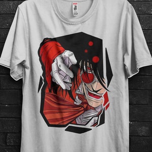 Può includere: T-shirt bianca con un'illustrazione in stile manga di un personaggio con capelli e abiti rossi, che indica con un dito. La maglietta è appesa a una gruccia nera contro un muro di mattoni neri. Il testo "BULK SALE" è visibile.