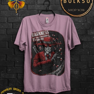 May include: A light purple t-shirt featuring a graphic of a character in a red suit and hat, surrounded by dark, eye-filled tentacles. The text "DARKNESS IS FULL OF MYSTERIES & SURPRISES" is displayed on the shirt.