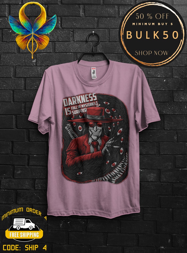 May include: A light purple t-shirt featuring a graphic of a character in a red suit and hat, surrounded by dark, eye-filled tentacles. The text "DARKNESS IS FULL OF MYSTERIES & SURPRISES" is displayed on the shirt.