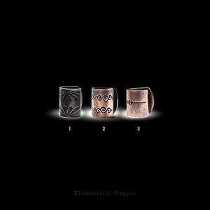 May include: Three copper-colored metal cuffs arranged horizontally, labeled 1, 2, and 3. Cuff 1 features a sunburst pattern, cuff 2 has a double swirl design, and cuff 3 displays a horizontal line with a central diamond. Text reads Elementally Copper.