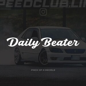 Peut inclure: Berline blanche avec le texte "Daily Beater" dans une police stylisée. L'image comprend également le texte "SPEEDCLUB.LIFE" et "PACK OF 2 DECALS". La voiture est sur une surface sombre, peut-être une route.