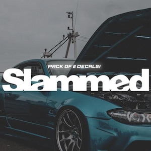 Puede incluir: Un coche azul verdoso con el capó abierto, mostrando el motor. El coche tiene una calcomanía blanca que dice "Slammed" con el texto "Pack of 2 Decals!" encima.