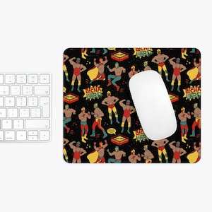 May include: A black mouse pad with a repeating pattern of wrestlers in colorful costumes. The wrestlers are wearing masks and are in various poses. The text "LUCHA LIBRE!" is repeated throughout the pattern.