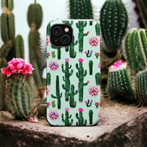May include: A phone case with a green and pink cactus print. The case has a camera cutout and a black border.