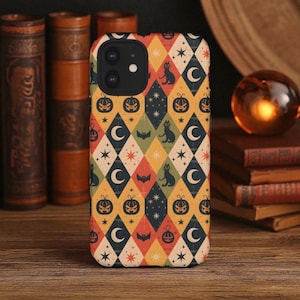 May include: A patterned phone case with a Halloween theme. The design includes repeating diamond shapes in orange, yellow, green, and red, with images of pumpkins, black cats, bats, crescent moons, and stars. The case is designed to fit a smartphone.